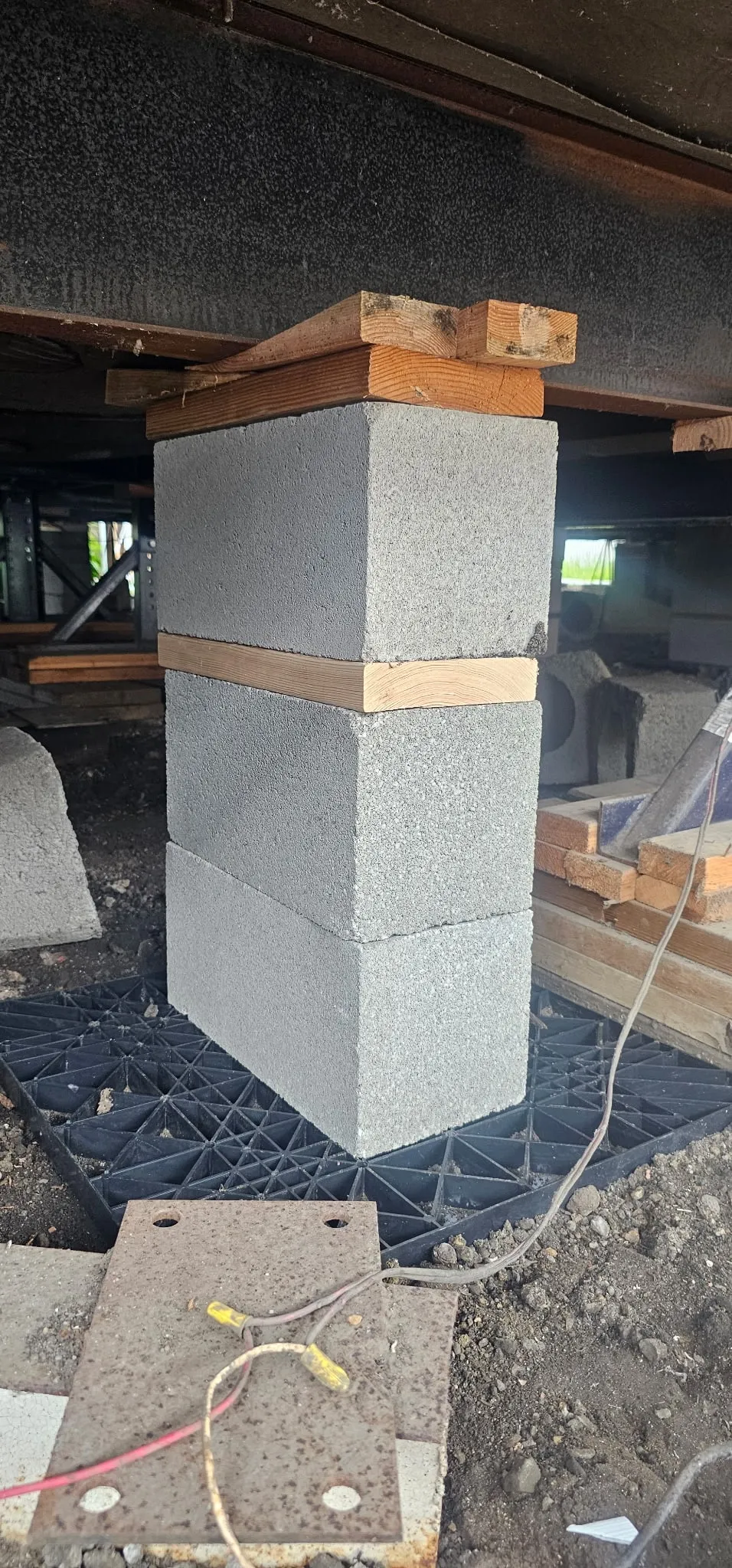 Concrete block pier with wood shims supporting a mobile home frame