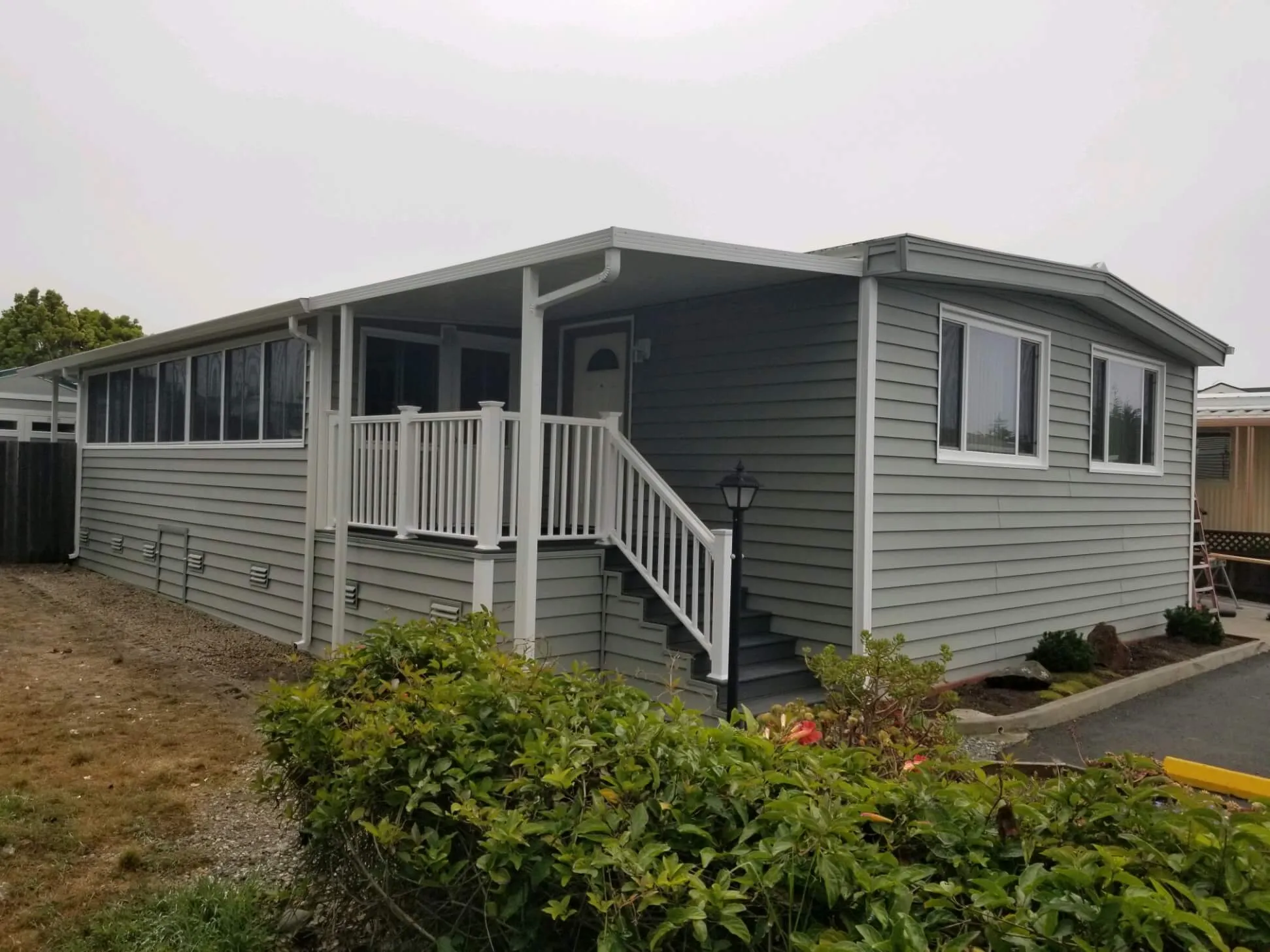 Gray mobile home with new siding, entry stairs and white vinyl railings